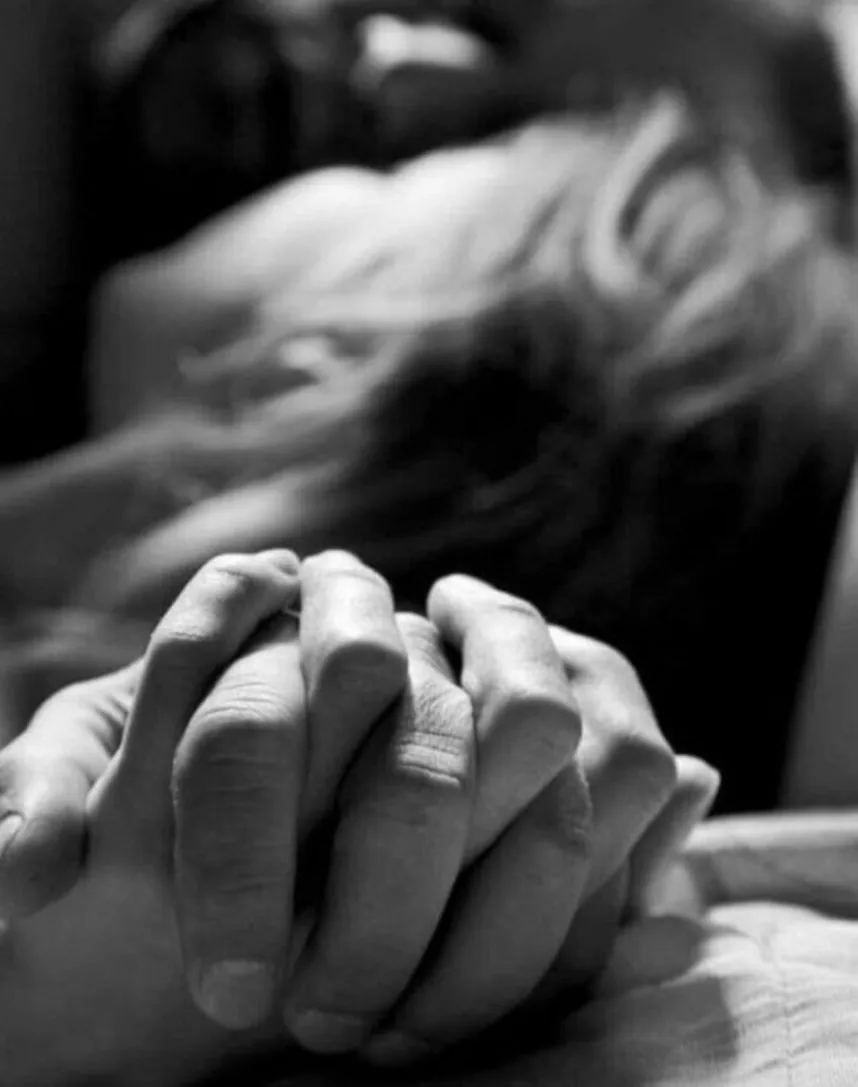 A black-and-white photograph of two people's hands clasped together, from the MutualClause campaign