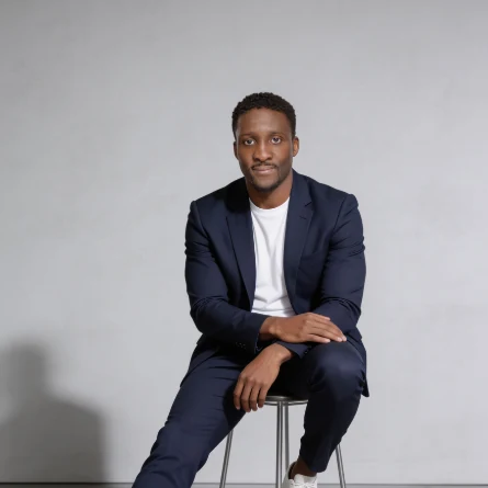 Wil, founder of YQR Design, seated in a navy suit in the studio